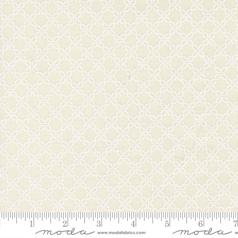 White geometric pattern on cream fabric with Moda label and ruler at the bottom.