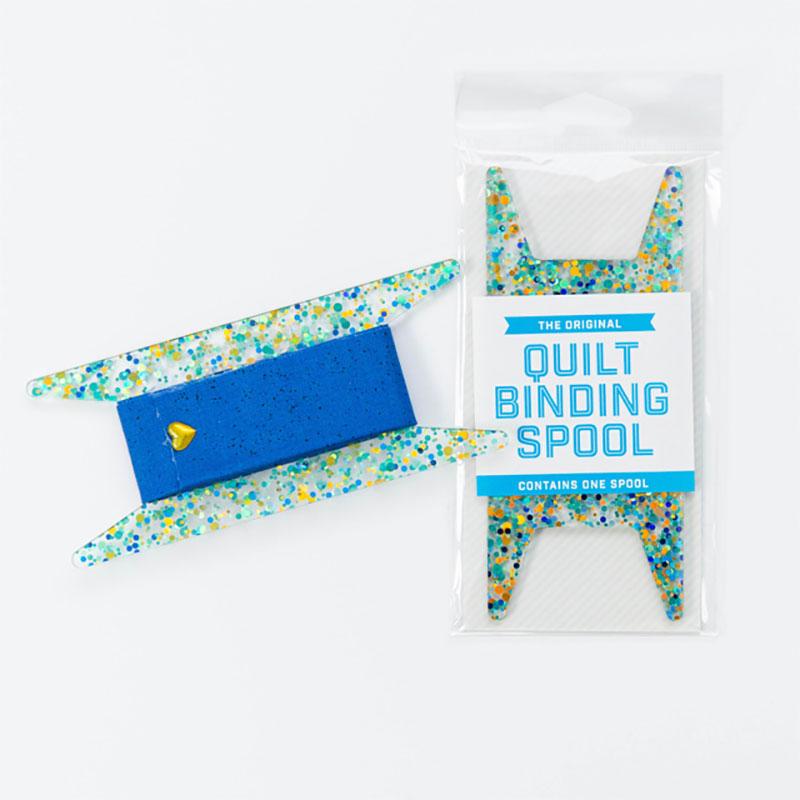 Picture of an acrylic quilt binding spool with teal, blue, and gold dots.