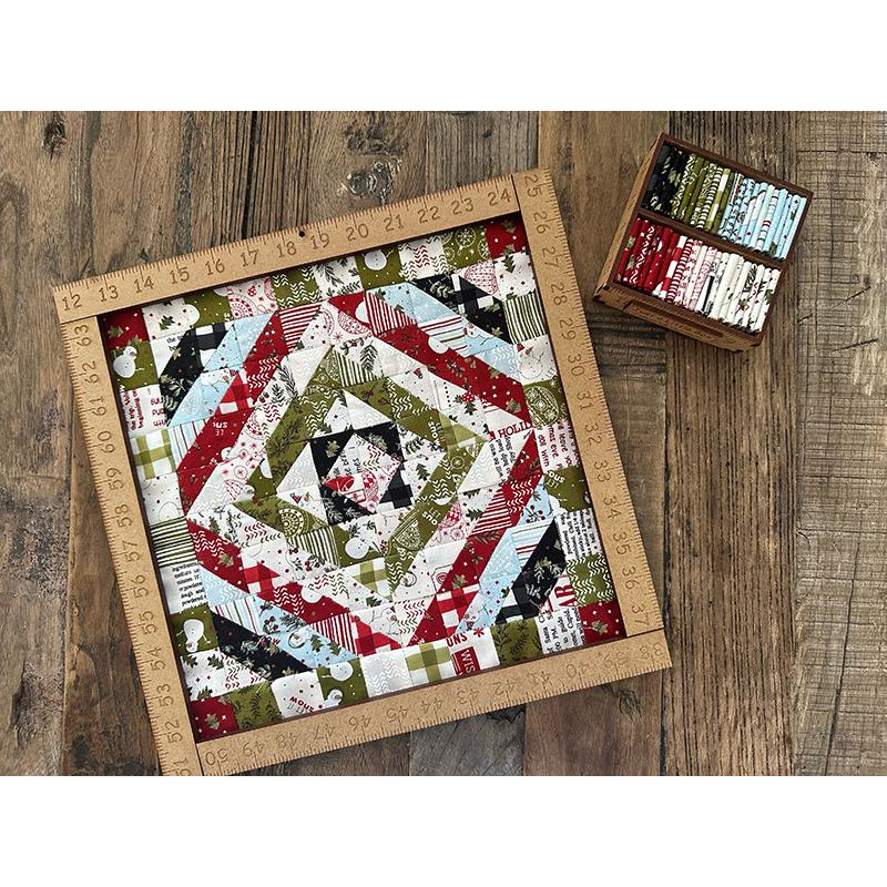Tiny Christmas themed around the world style quilt on a wooden surface with a ruler and fabric swatches.