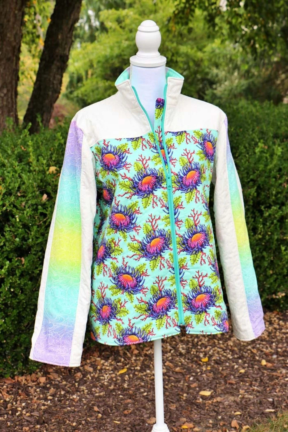 Colorful jacket with floral pattern on a mannequin outdoors.