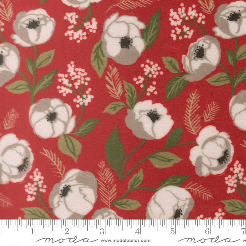 Polyester fabric swatch with white roses and christmas foliage on a red background with a ruler for scale.
