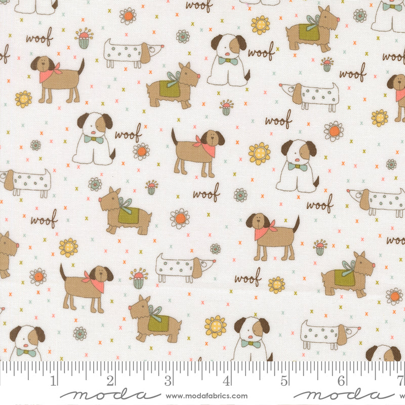 Fabric pattern with cartoon dogs and 'woof' text on a white background, featuring Moda label and ruler for scale.