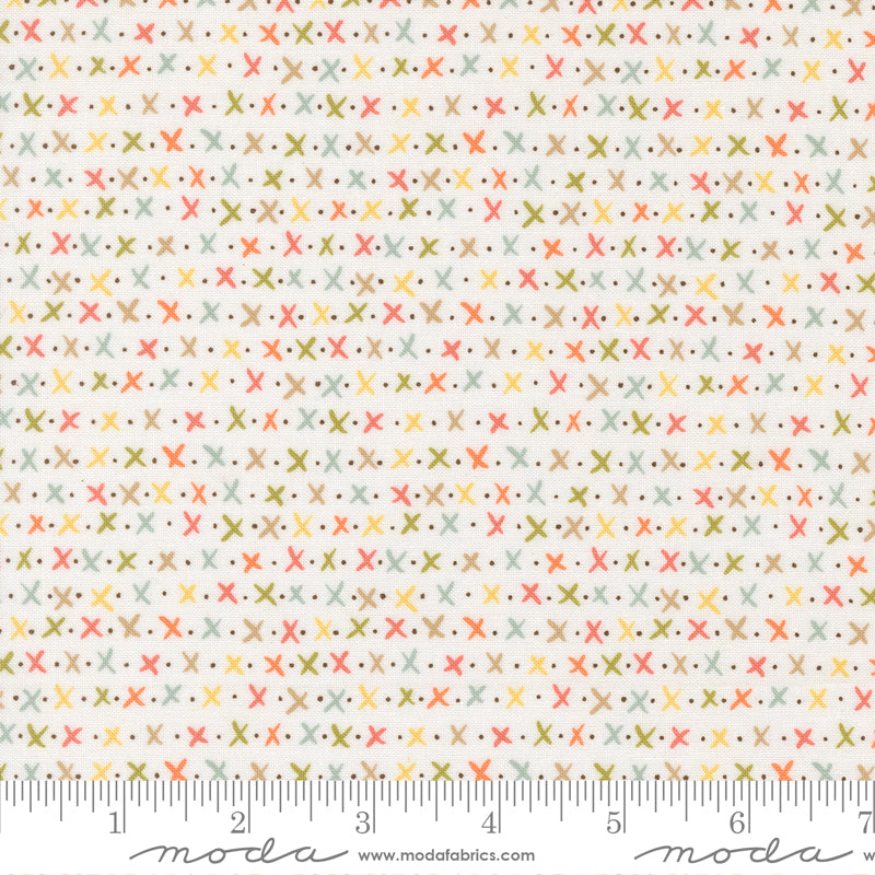 Fabric with a pattern of small crosses and dots on a white background, featuring ruler for scale.