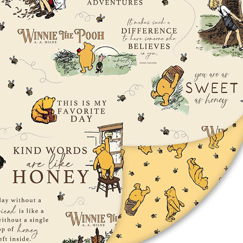 Winnie the Pooh-themed double sided cuddle fabric with illustrations and text on a beige background on one side, and a bear with bees and honey pots on the other.
