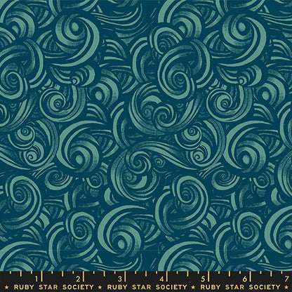 Patterned fabric with swirling designs in teal on a blue background with a ruler for scale.