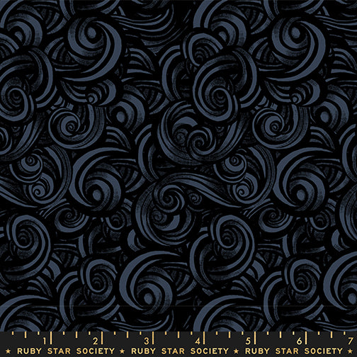 Patterned fabric with swirling designs in gray and black on a black background with a ruler for scale.